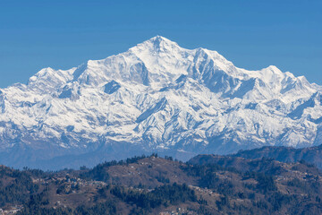 a mountain range with a river running through it and snow capped mountains in the background, with a blue sky