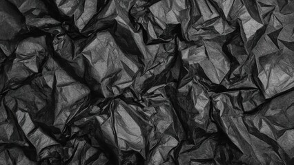 Texture of crumpled black paper with deep folds and wrinkles close-up, perfect for backgrounds, design projects, packaging, and artistic compositions with dark moody atmosphere