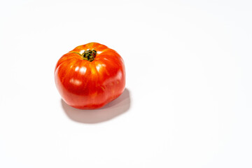 A perfectly ripe, red tomato isolated on a clean white background.