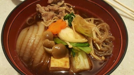 Sukiyaki, boiling vegetables including cabbage, konjac noodle, onion, carrot, shiitake  and tofu in...