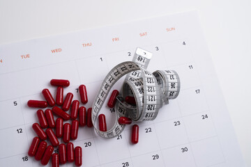 Measuring tape and tablets, vitamins on a light background with space for text. Concept of losing...