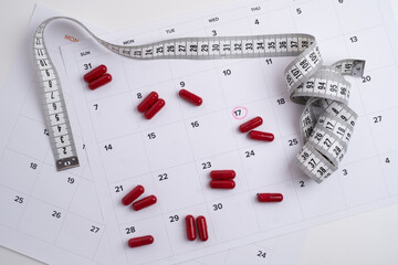 Measuring tape and tablets, vitamins on a light background with space for text. Concept of losing...
