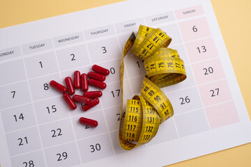 Measuring tape and tablets, vitamins on a light background with space for text. Concept of losing...