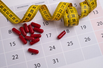Measuring tape and tablets, vitamins on a light background with space for text. Concept of losing...
