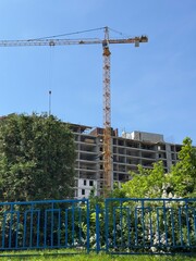 Construction site with yellow crane and unfinished building. Urban development captured under clear blue sky.