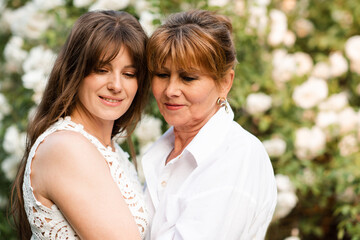 Close up portrait of smiling young adult woman 30-35 year old holding senior female 55-60 year old...