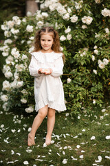 Cute  smiling child girl 4-5 year old wearing stylish vintage dress holding rose flowers in hands...