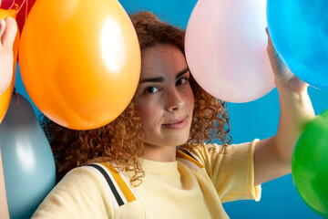 Joyful redhead girl celebrating with colorful balloons