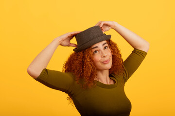 Redhead woman enjoying with stylish hat in studio