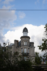 Elegant historic building featuring a distinctive dome tower set against a blue sky with clouds.