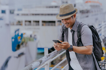 Tourist asian man backpacker enjoying solo travel vacation using cell phone on the ship. Tourism...