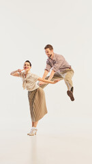 A couple joyfully performs vintage swing dance in elegant retro costumes, radiating lively...