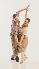 A joyful couple performs swing dance, dressed in vintage attire, showcasing energetic and graceful...