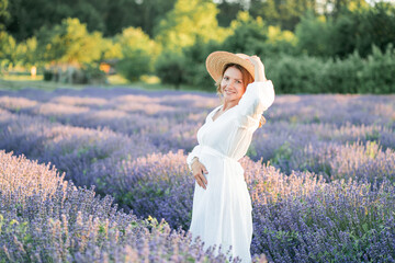 Beautiful woman enjoying summer breeze in lavender field. Portrait of blonde in sunlight....