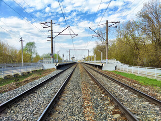 The train tracks stretch out into the horizon, flanked by lush greenery and a vibrant blue sky.