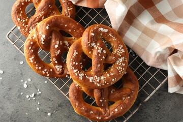 Tasty pretzels with salt on grey table, top view