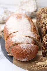Freshly baked loaves of bread and spike on white table, closeup