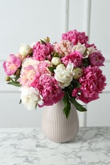 Bouquet of beautiful peonies in vase on white marble table indoors