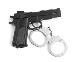 Gun and handcuffs on white background, top view. Police equipment