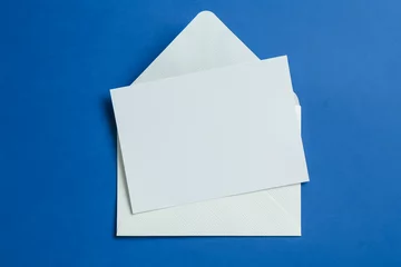  Blank invitation card and envelope on blue background, top view. Space for design © New Africa