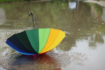 Colorful umbrella on wet asphalt under heavy rain. Space for text