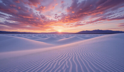 A breathtaking sunset over white sand dunes. Vibrant pink and purple clouds fill the sky, creating a dramatic and serene landscape.