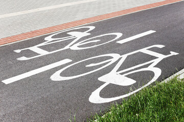 Dedicated bicycle lane on asphalt road. White bike symbol painted on black street surface. Urban...