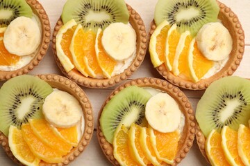 Tartlets with fruits on table, top view. Delicious dessert
