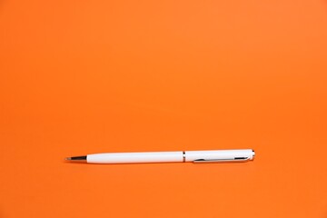 One white pen on orange background, space for text