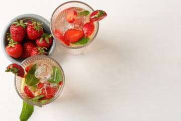 Tasty refreshing drink with strawberries, lemon and mint on white table, flat lay. Space for text