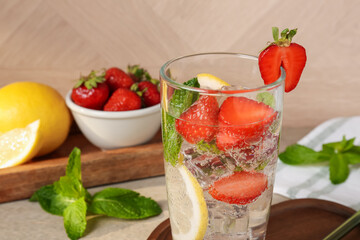 Tasty refreshing drink with strawberries, lemon and mint on table, closeup