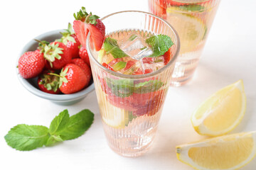 Tasty refreshing drink with strawberries, lemon and mint on white table, above view