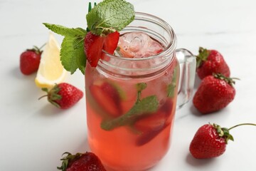 Refreshing drink with strawberries, ice and mint on white table, closeup