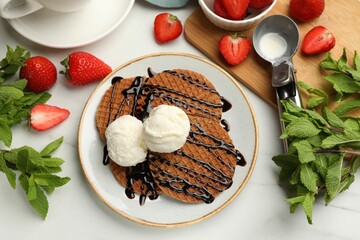 Tasty Dutch waffles (stroopwafels) with ice cream, chocolate sauce, mint and strawberries on white...