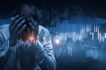 A man clutches his head in distress as stock charts plunge behind him, symbolizing financial loss in a digital global network
