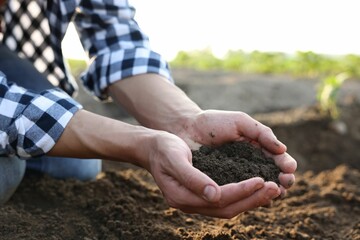 Man holding pile of soil in field, closeup