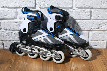 Pair of roller skates on wooden table near white brick wall