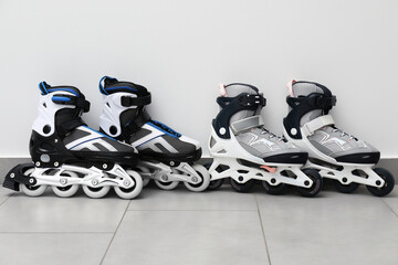 Pairs of roller skates on floor near white wall