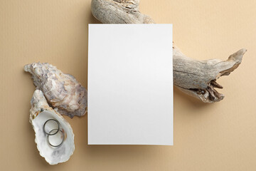 Wedding invitation card, silver rings and decor on beige background, flat lay