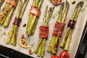 Tasty cooked asparagus with bacon, tomatoes and spices in baking tray, top view