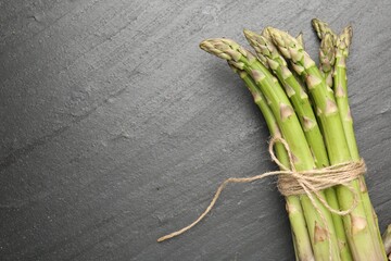 Fresh raw asparagus spears on black table, top view. Space for text