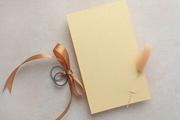 Wedding invitation card with spike and silver rings on color textured table, top view