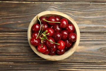 Fresh wet cherries in bowl on wooden table, top view