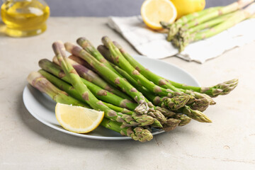 Fresh raw asparagus and lemon on light grey table, closeup