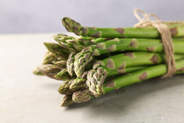 Fresh raw asparagus on light grey table, closeup