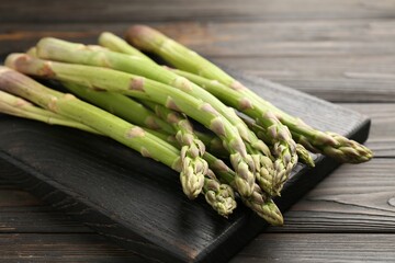 Fresh raw asparagus on black wooden table, closeup