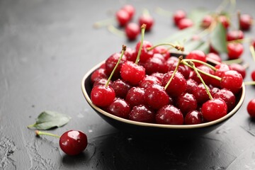 Wet ripe cherries on black table, closeup
