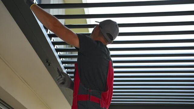 Man Maintains Outdoor Aluminium Patio Pergola  Structure With Careful Adjustments in Sunny Weather