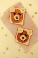 Funny cute bear faces sandwich toast bread with peanut butter, banana,nuts. Kids childrens baby's sweet dessert healthy breakfast lunch food art on plate,close up,top view