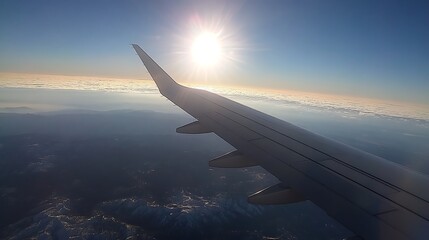 Obraz premium Airplane Wing View Of Landscape With Bright SunLight And Cityscape On Horizon View From High Altitude Overview With Bright Skies And Sun Glare On Wing Showing Travel And